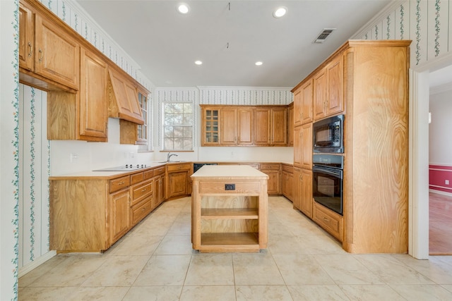 kitchen featuring a center island, visible vents, a sink, black appliances, and wallpapered walls