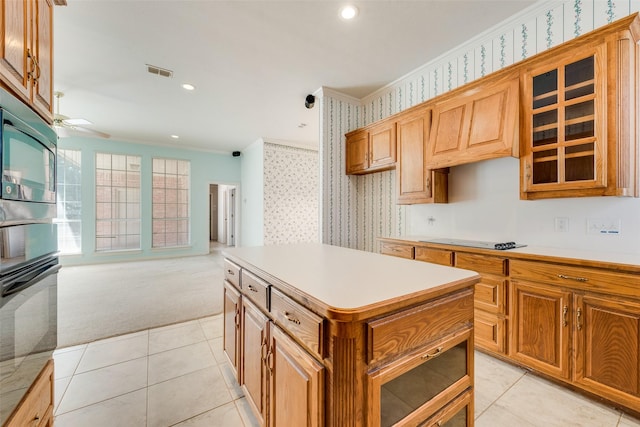 kitchen featuring visible vents, ornamental molding, glass insert cabinets, black appliances, and wallpapered walls