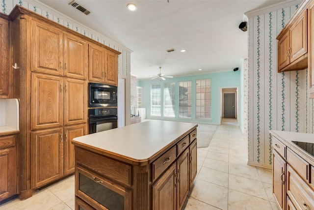 kitchen with a kitchen island, visible vents, ornamental molding, black appliances, and brown cabinetry