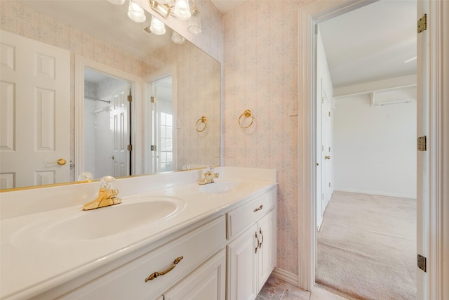 full bath with baseboards, double vanity, a sink, and wallpapered walls