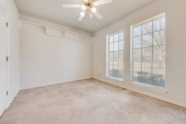 empty room featuring light carpet, ceiling fan, and baseboards