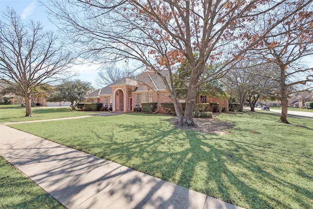 view of front of home featuring brick siding and a front lawn