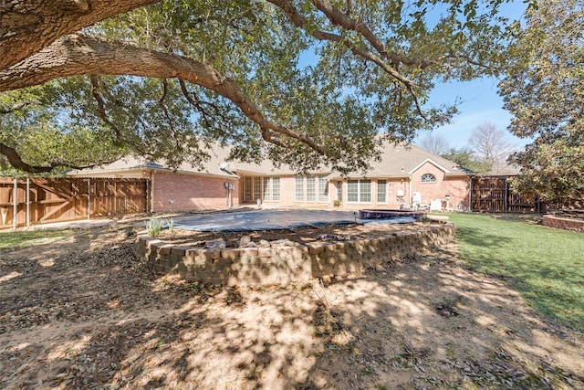 view of front of house with a fenced backyard, a front yard, and brick siding