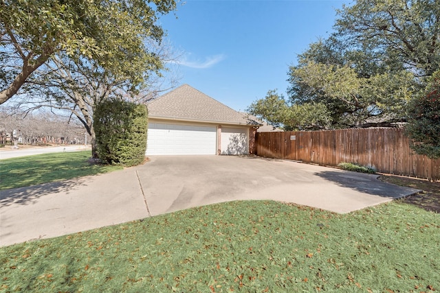 view of side of property with a garage, fence, concrete driveway, a yard, and roof with shingles