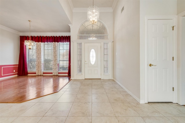 tiled foyer featuring baseboards, ornamental molding, visible vents, and an inviting chandelier