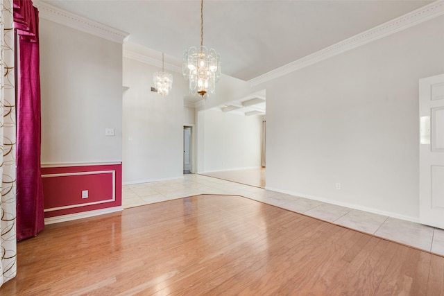 spare room featuring a chandelier, crown molding, baseboards, and wood finished floors