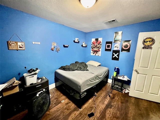 bedroom featuring dark hardwood / wood-style flooring and a textured ceiling