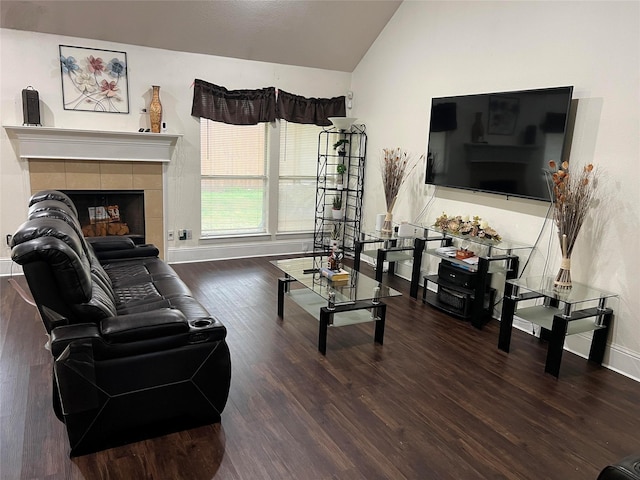 living room with dark hardwood / wood-style flooring, a tiled fireplace, and lofted ceiling