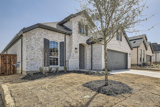 french provincial home with brick siding, concrete driveway, a garage, and fence