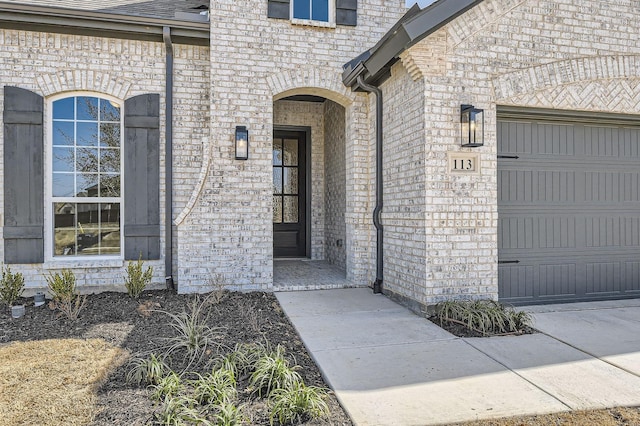 property entrance featuring brick siding, a garage, and roof with shingles