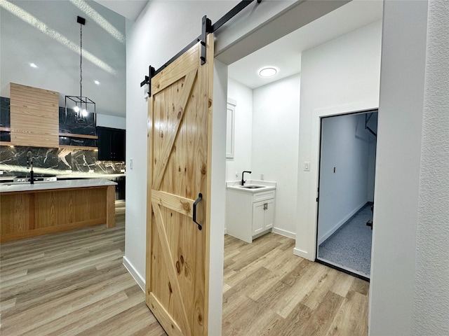 interior space featuring a barn door, sink, pendant lighting, and light wood-type flooring