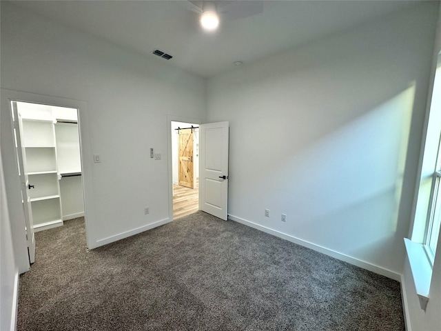 unfurnished bedroom featuring dark carpet, a closet, and a spacious closet