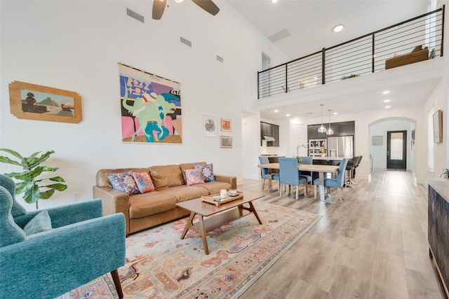 living room featuring light wood finished floors, visible vents, and arched walkways