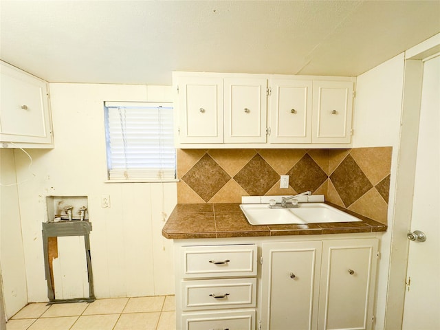 kitchen with light tile patterned floors, sink, white cabinetry, and backsplash