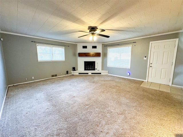 unfurnished living room with ceiling fan, carpet flooring, crown molding, and a large fireplace
