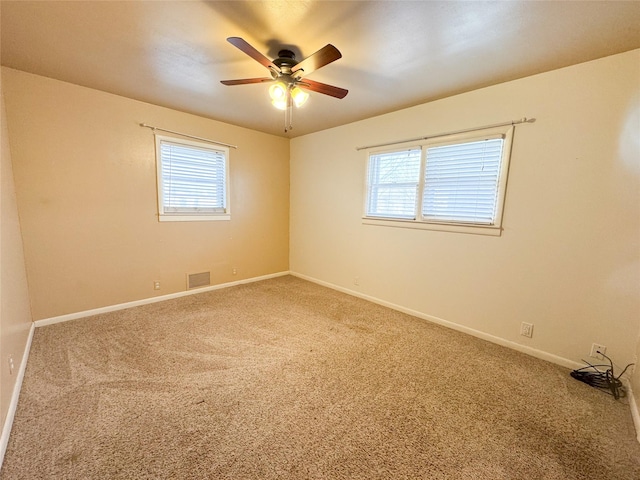 carpeted spare room with plenty of natural light and ceiling fan