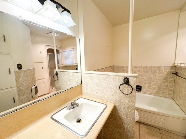 bathroom with tile walls, a bathing tub, sink, and tile patterned floors