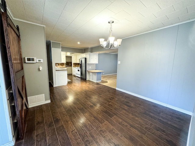 kitchen with a chandelier, white cabinetry, pendant lighting, a barn door, and stainless steel fridge