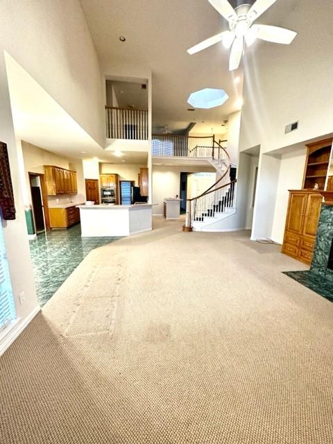 interior space with ceiling fan, carpet flooring, and a high ceiling