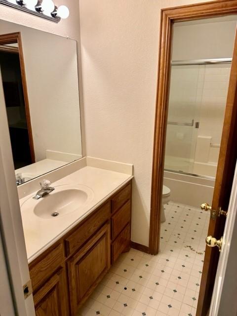 full bathroom featuring enclosed tub / shower combo, vanity, and toilet