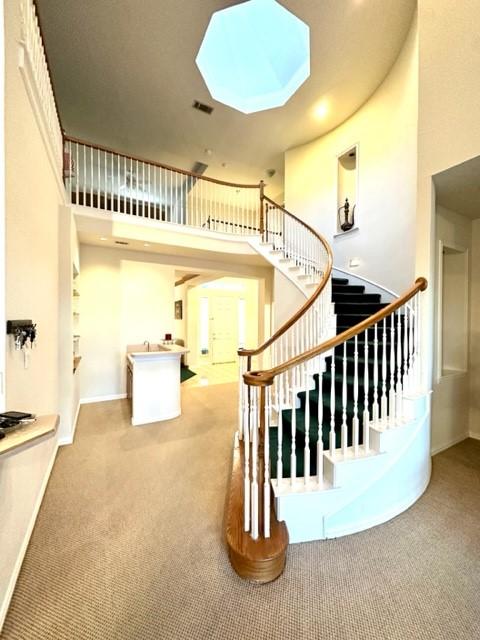 stairs with a skylight, carpet floors, and a towering ceiling