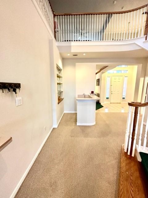 interior space featuring light carpet and a towering ceiling