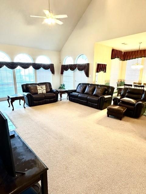 carpeted living room with high vaulted ceiling and ceiling fan