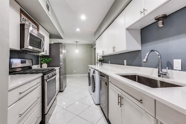 kitchen with appliances with stainless steel finishes, sink, white cabinetry, and separate washer and dryer