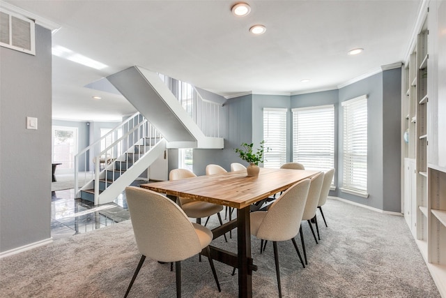 carpeted dining room with ornamental molding