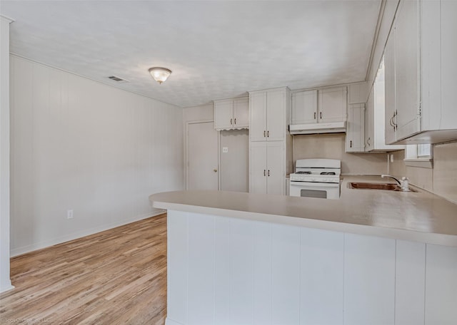 kitchen with white cabinets, white range with gas cooktop, and kitchen peninsula