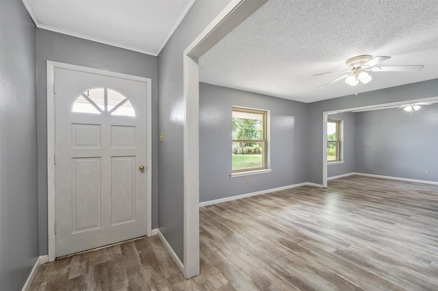 entrance foyer with a textured ceiling, ceiling fan, crown molding, and light hardwood / wood-style floors