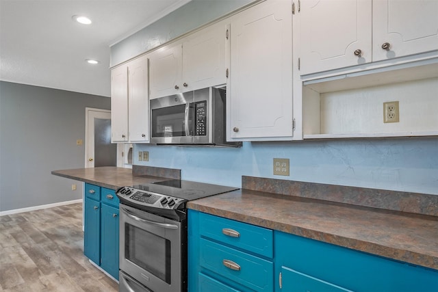 kitchen with blue cabinets, stainless steel appliances, white cabinetry, and light wood-type flooring
