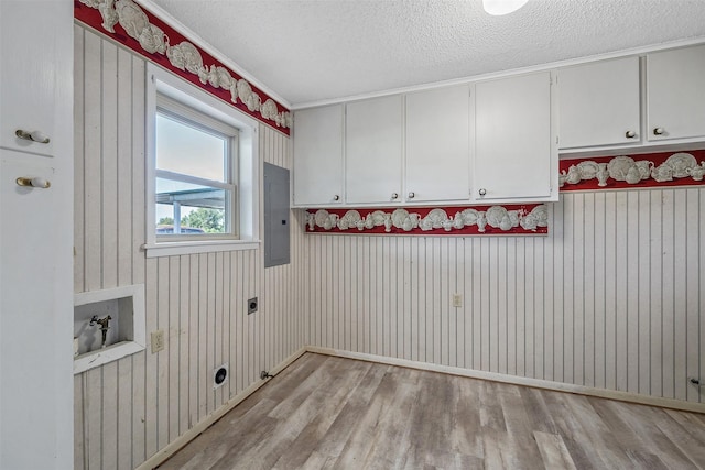 clothes washing area with light wood-type flooring, cabinets, hookup for an electric dryer, electric panel, and a textured ceiling
