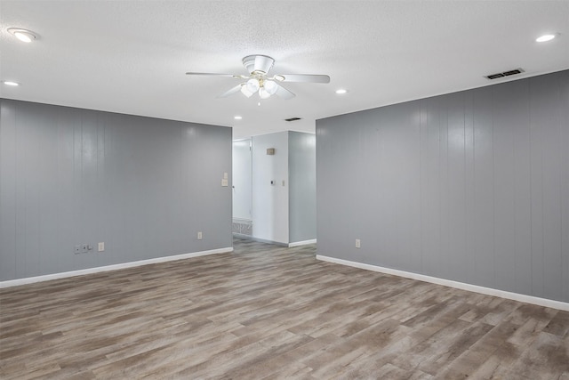 spare room featuring ceiling fan, light wood-type flooring, and a textured ceiling