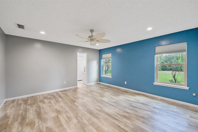 unfurnished room with light wood-type flooring, plenty of natural light, and a textured ceiling
