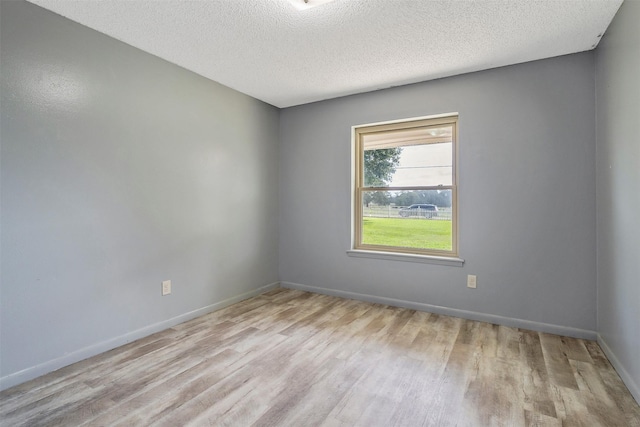 unfurnished room with light hardwood / wood-style flooring and a textured ceiling