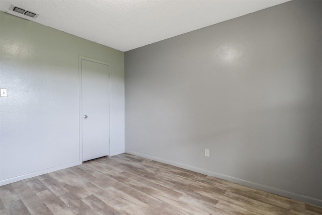 unfurnished room with light wood-type flooring and a textured ceiling