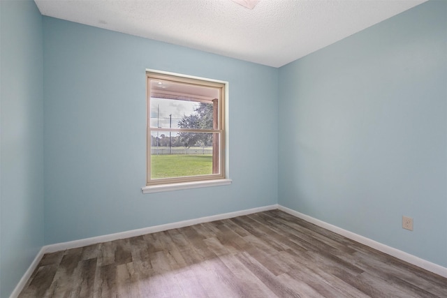 spare room with a textured ceiling and hardwood / wood-style floors