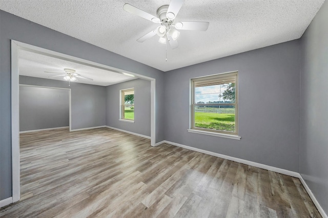 empty room with light wood-type flooring, ceiling fan, and a textured ceiling