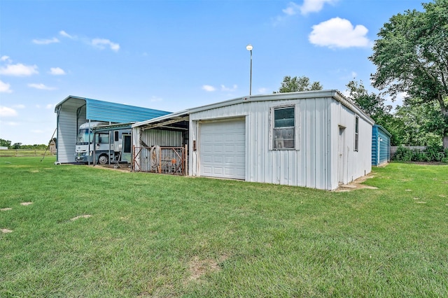 view of outdoor structure with a yard, a carport, and a garage