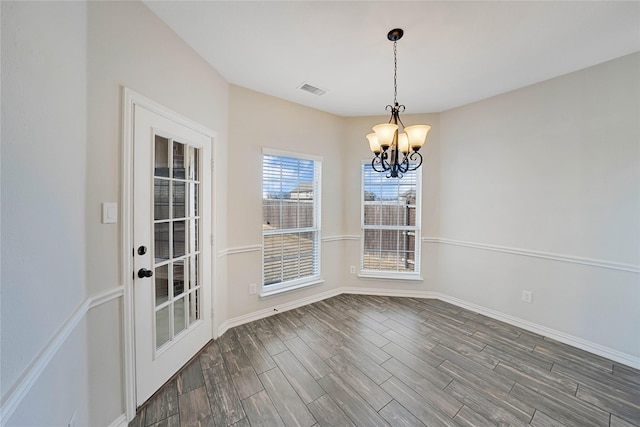 unfurnished dining area featuring dark wood-type flooring and a notable chandelier