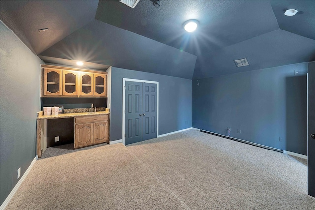 additional living space featuring vaulted ceiling and light colored carpet