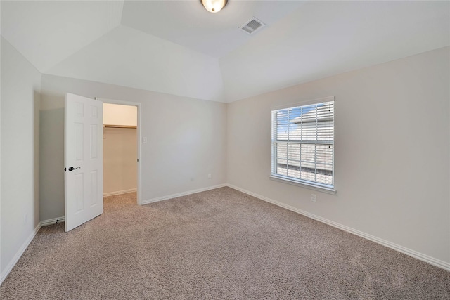 unfurnished bedroom featuring vaulted ceiling, carpet floors, and a walk in closet