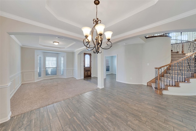 interior space featuring a tray ceiling, ornamental molding, and an inviting chandelier