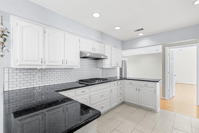 kitchen with white cabinets, kitchen peninsula, stainless steel gas cooktop, and decorative backsplash