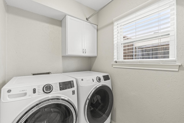 clothes washing area featuring cabinets and washer and dryer