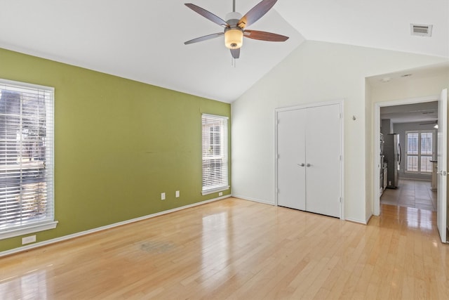 unfurnished bedroom featuring light wood-type flooring, vaulted ceiling, ceiling fan, and stainless steel fridge