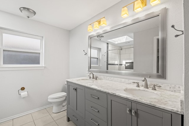 bathroom with vanity, a tile shower, a skylight, toilet, and tile patterned floors