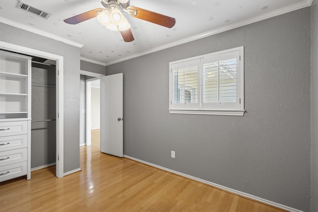 unfurnished bedroom featuring light wood-type flooring, a closet, crown molding, and ceiling fan