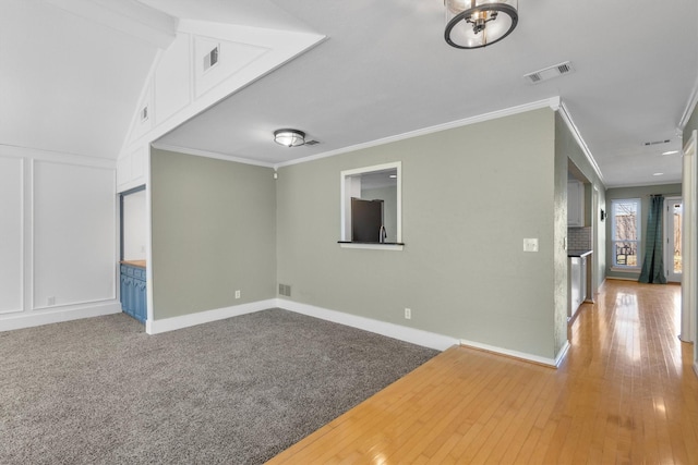 empty room with ornamental molding, a brick fireplace, and light hardwood / wood-style floors